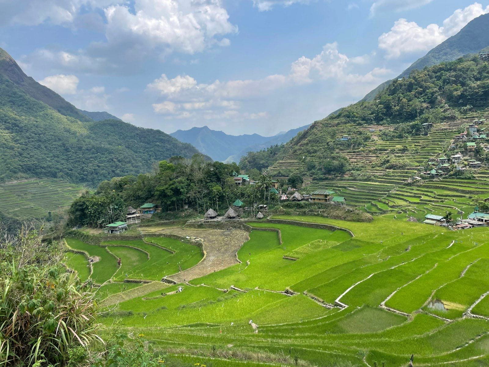 Green rice terraces and a village of native houses at Batad, Ifugao, under a cloudy sky