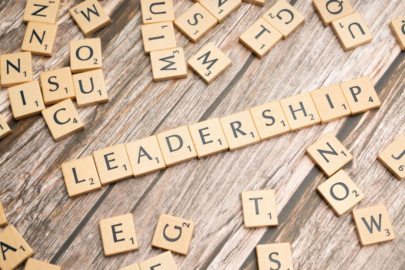 Wooden letter tiles spelling LEADERSHIP across a weathered wooden table